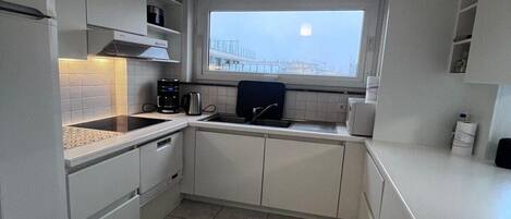 A compact kitchen with white cabinets, a window, and a built-in oven.