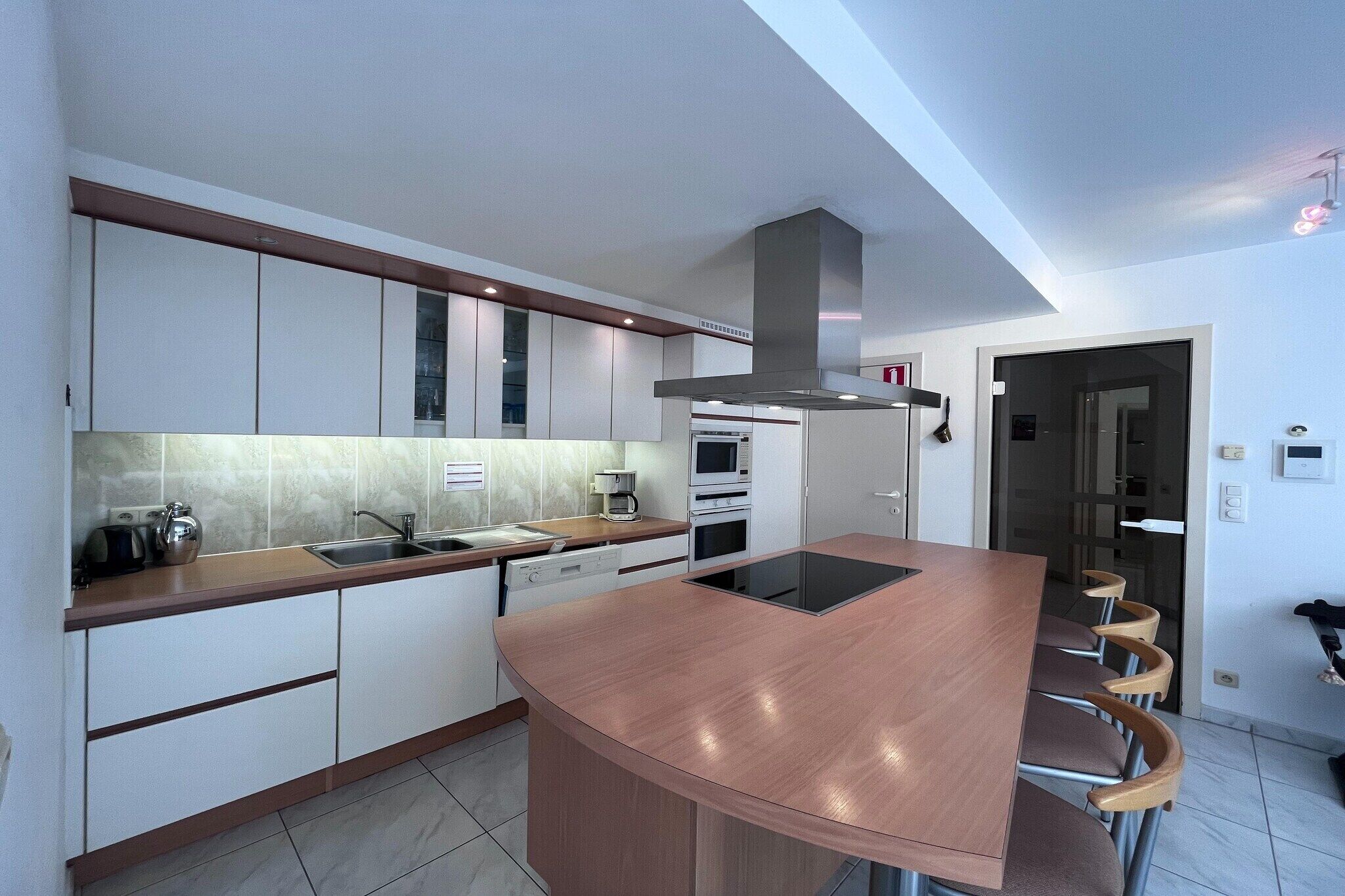 Een moderne keuken met een gebogen kookeiland, ingebouwde apparatuur en een bar voorzien van barkrukken.