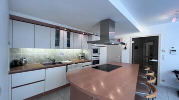 Een moderne keuken met een gebogen kookeiland, ingebouwde apparatuur en een bar voorzien van barkrukken.