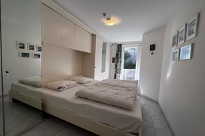 Ein Schlafzimmer mit Bett, Kleiderschrank, Fenster und Bildern an der Wand.