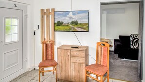 Ein Zimmer mit einem Holzschrank, zwei Stühlen, einem an der Wand befestigten Fernseher und einer Tür.