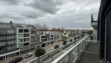 Ein modernes Gebäude mit einem Glasbalkon mit Blick auf eine Straße mit Autos und anderen Gebäuden.