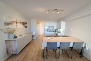 Een moderne keuken met een eethoek, witte kasten en een licht houten vloer.