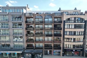 Een meerlaags gebouw met balkons, een winkelgefacade met een bord en een zichtbare ingang.