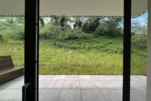 An open patio with a view of a grassy area and trees. - Couples Retreat Near the Dunes (OOSTDUINKERKE)
