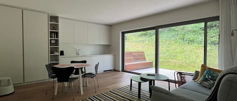 Un intérieur moderne comprenant un coin repas, une cuisine et une grande porte-fenêtre coulissante donnant sur un espace extérieur.