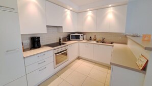 Een moderne keuken met witte kasten, een magnetron, een koffiezetapparaat en een spoelbak.
