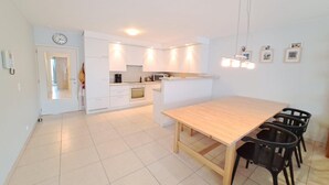 Een moderne keuken met witte kasten, een houten eettafel en zwarte stoelen.