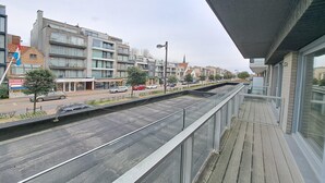 Een modern gebouw met een balkon dat uitkijkt over een straat.