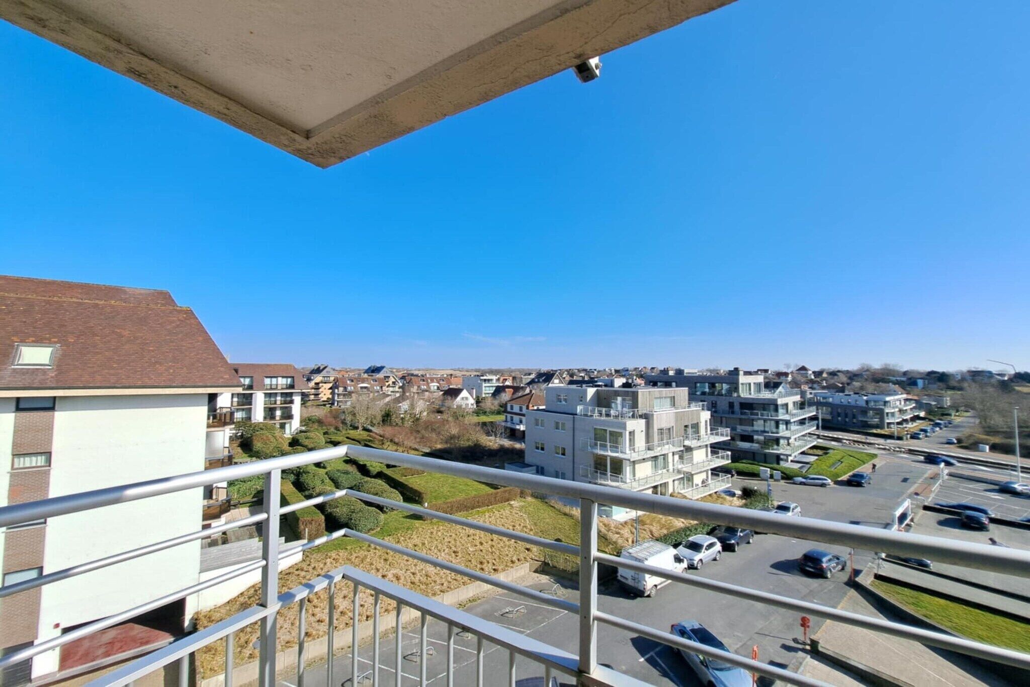 Zona residencial con edificios modernos, un estacionamiento y un cielo azul despejado.