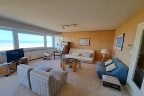 Ein Wohnzimmer mit Fernseher, Sofas, einem Couchtisch und Meerblick.