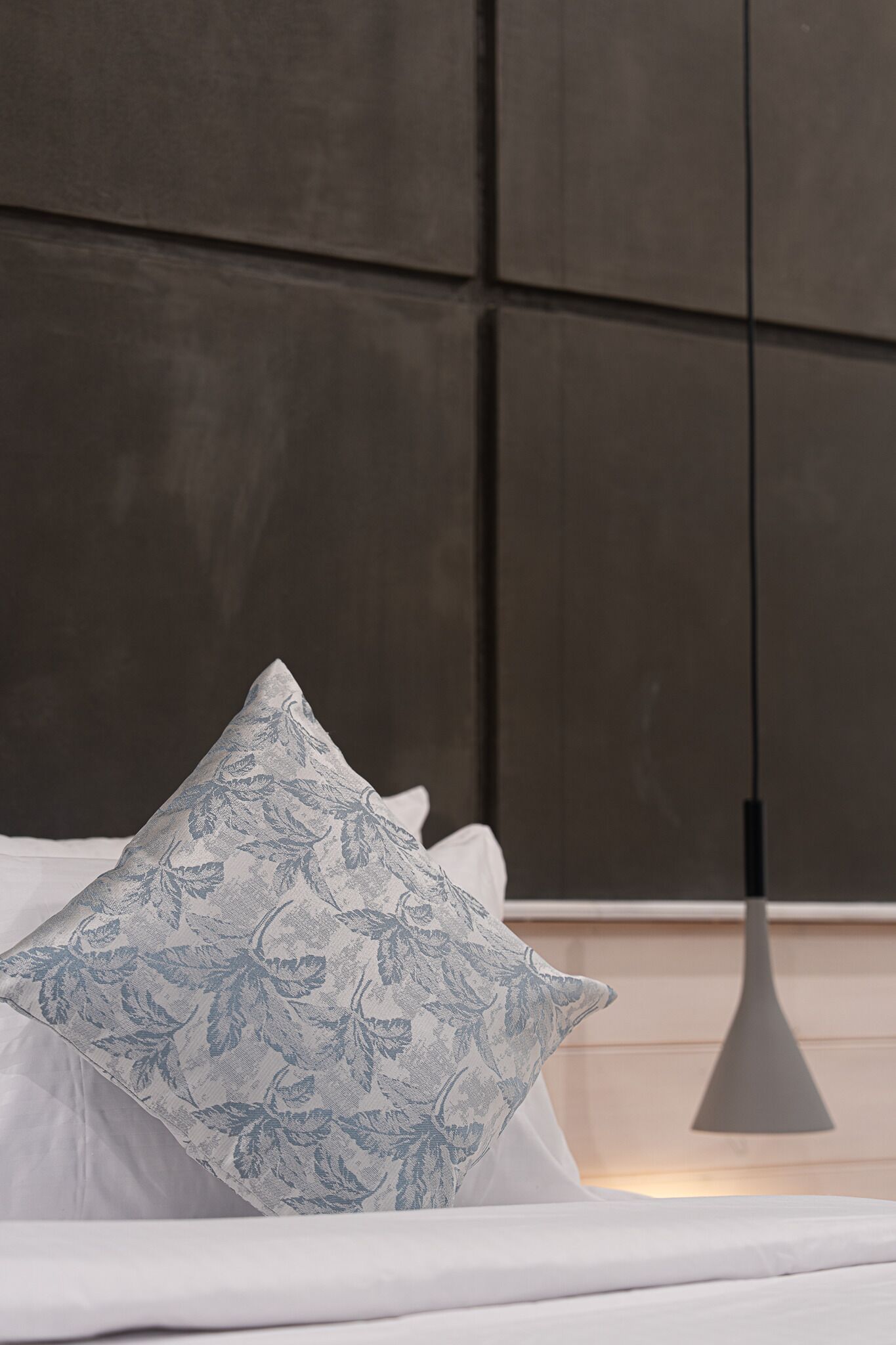 A bed with a white mattress and a single patterned pillow.