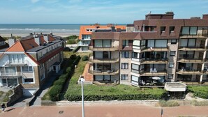 A multi-story residential building with balconies, a beach view, and a parking area. - Family Apartment in Groenendijk (OOSTDUINKERKE)