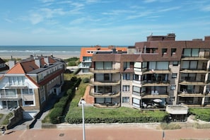 Ein mehrgeschossiges Wohngebäude mit Balkonen, Blick auf den Strand und einem Parkplatz.