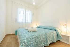 Ein Schlafzimmer mit einem Bett, zwei Nachttischlampen, einem Fenster mit Vorhängen und einem Nachttisch.