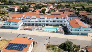 Ein modernes Hotel mit mehreren Etagen, einem Schwimmbad und Blick auf die umliegende Landschaft.