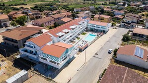 Ein modernes Hotel mit Schwimmbad, mehreren Etagen und Blick auf die umliegende Wohngegend und Berge.