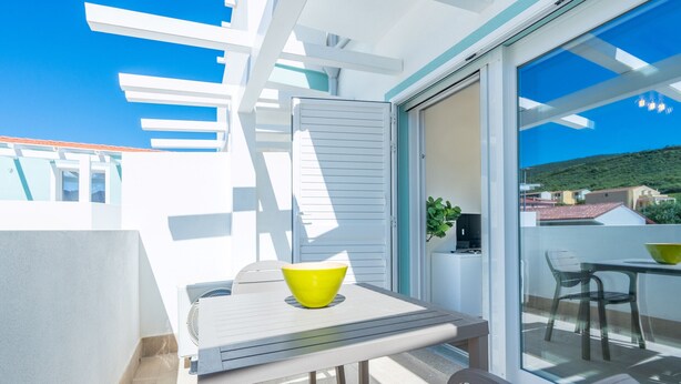 Ein Balkon mit Tisch, Stühlen, einer gelben Schüssel und einem Blumentopf.