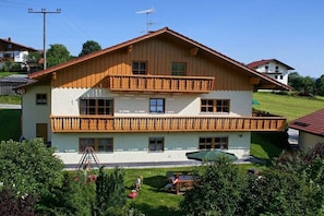 Ein zweistöckiges Gebäude mit Balkon, kleinem Garten und Schaukel.