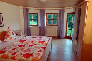 Ein Schlafzimmer mit einem Bett, einem Heizkörper und zwei mit Vorhängen versehenen Fenstern.