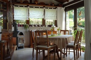Ein Essbereich mit Tisch, Stühlen, einem Kamin und Blick ins Freie.