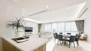 Una sala de estar moderna con comedor, televisor y un amplio ventanal con cortinas.