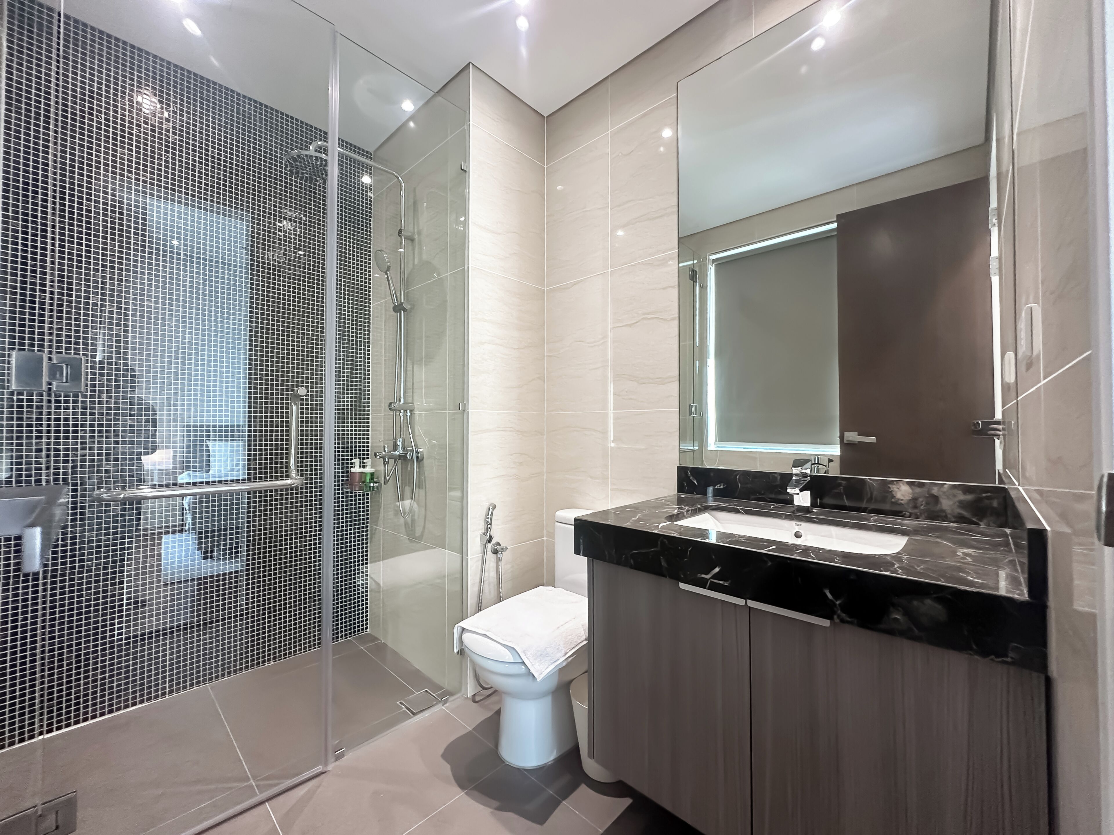 Une salle de bain moderne avec une douche à parois de verre, un grand miroir et un comptoir en marbre.