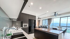 Una cocina moderna con una isla central, electrodomésticos integrados y vistas a un paisaje urbano a través de amplios ventanales.