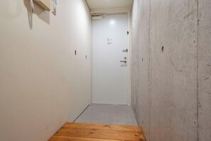 A narrow hallway with a wooden floor, white walls, and a door at the end. - T-FLAT NAMBA WEST (Sakuragawa, Naniwa)