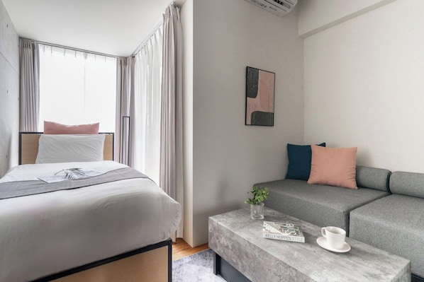 A modern hotel room with a bed, a sofa, a coffee table, and a framed picture on the wall. - T-FLAT NAMBA WEST (Sakuragawa, Naniwa)