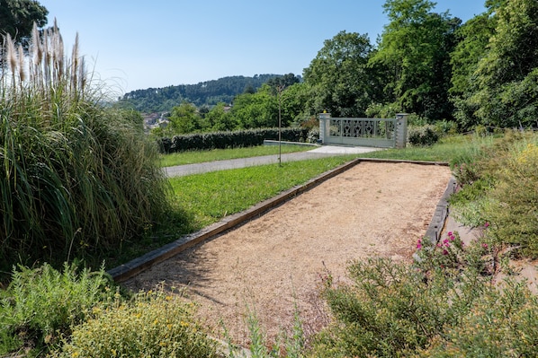 A garden with a gravel area, a metal gate, and surrounding greenery.