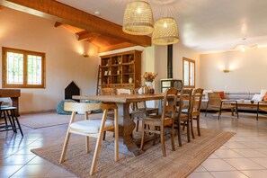 A spacious living room with a wooden dining table, chairs, a bookshelf, and a sofa. - Villa "De L’Olivier" with Private Pool, Wi-Fi, and Air Conditioning (Labégude)