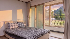 A bedroom with a bed, a window with a view of the outdoors, and a balcony with a railing. - Chuncheon O2 Pension (Chuncheon)