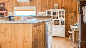 A kitchen with wooden cabinets, a white refrigerator, and a small dining area with a chair and table. - Gorgeous home in Slagelse with house sea view (Slagelse)