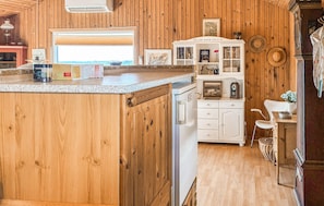 A kitchen with wooden cabinets, a white refrigerator, and a small dining area with a chair and table. - Gorgeous home in Slagelse with house sea view (Slagelse)