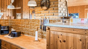 A kitchen with wooden cabinetry, a tiled backsplash, hanging knives, and a coffee maker. - Gorgeous home in Slagelse with house sea view (Slagelse)
