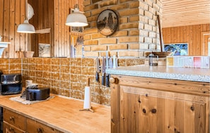 A kitchen with wooden cabinetry, a tiled backsplash, hanging knives, and a coffee maker. - Gorgeous home in Slagelse with house sea view (Slagelse)