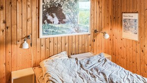 A wooden-paneled room with a bed, a window with a view of greenery, a framed painting, and a desk lamp. - Gorgeous home in Slagelse with house sea view (Slagelse)