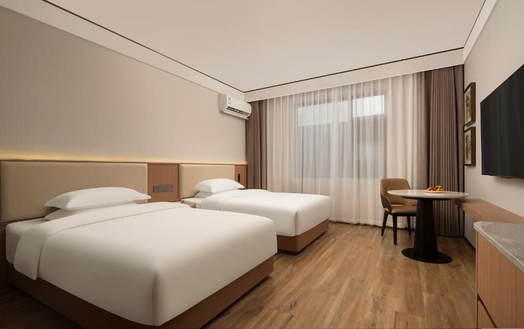 Habitación de hotel con dos camas, un escritorio y una silla.