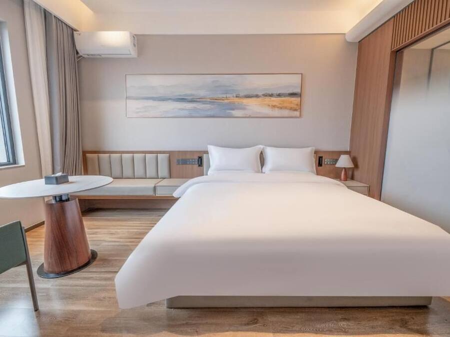 Ein modernes Hotelzimmer mit einem großen Bett, einem runden Tisch, einer Couch und einem Bild an der Wand.