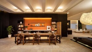 Un comedor moderno con una mesa larga y sillas, una estantería y un panel decorativo en la pared.