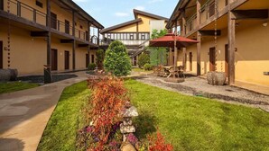 Un patio con un sendero central, un pequeño árbol y una zona de estar con una mesa y sillas.
