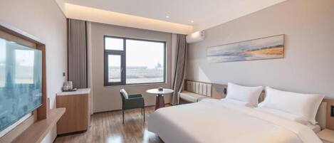 Une chambre d’hôtel avec un grand lit, un coin salon comprenant une chaise et une petite table, une télévision et une grande fenêtre.