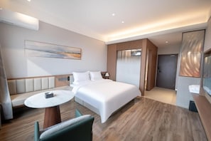 A modern hotel room with a large bed, a seating area with a table, and a view of the city. - YUNMANJIANYE HOTEL (Xianyang)