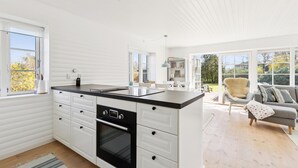 A modern kitchen with white cabinetry, a black oven, and a large island. - 3 bedroom lovely home in Slagelse (Slagelse)