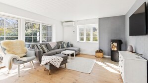 A modern living room with a sofa, armchair, and fireplace. - 3 bedroom lovely home in Slagelse (Slagelse)