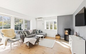 Ein modernes Wohnzimmer mit Sofa, Sessel und Kamin.