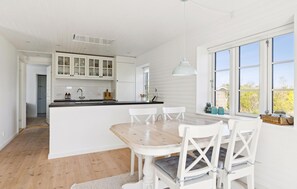 Eine moderne Küche mit weißen Schränken, einem Holztisch und einem großen Fenster mit Aussicht.