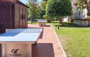 Ein Tischtennis-Tisch, eine Bank und ein Gebäude mit heruntergelassenen Rollläden.