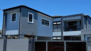 A modern two-story building with a garage, a balcony, and a clear blue sky.